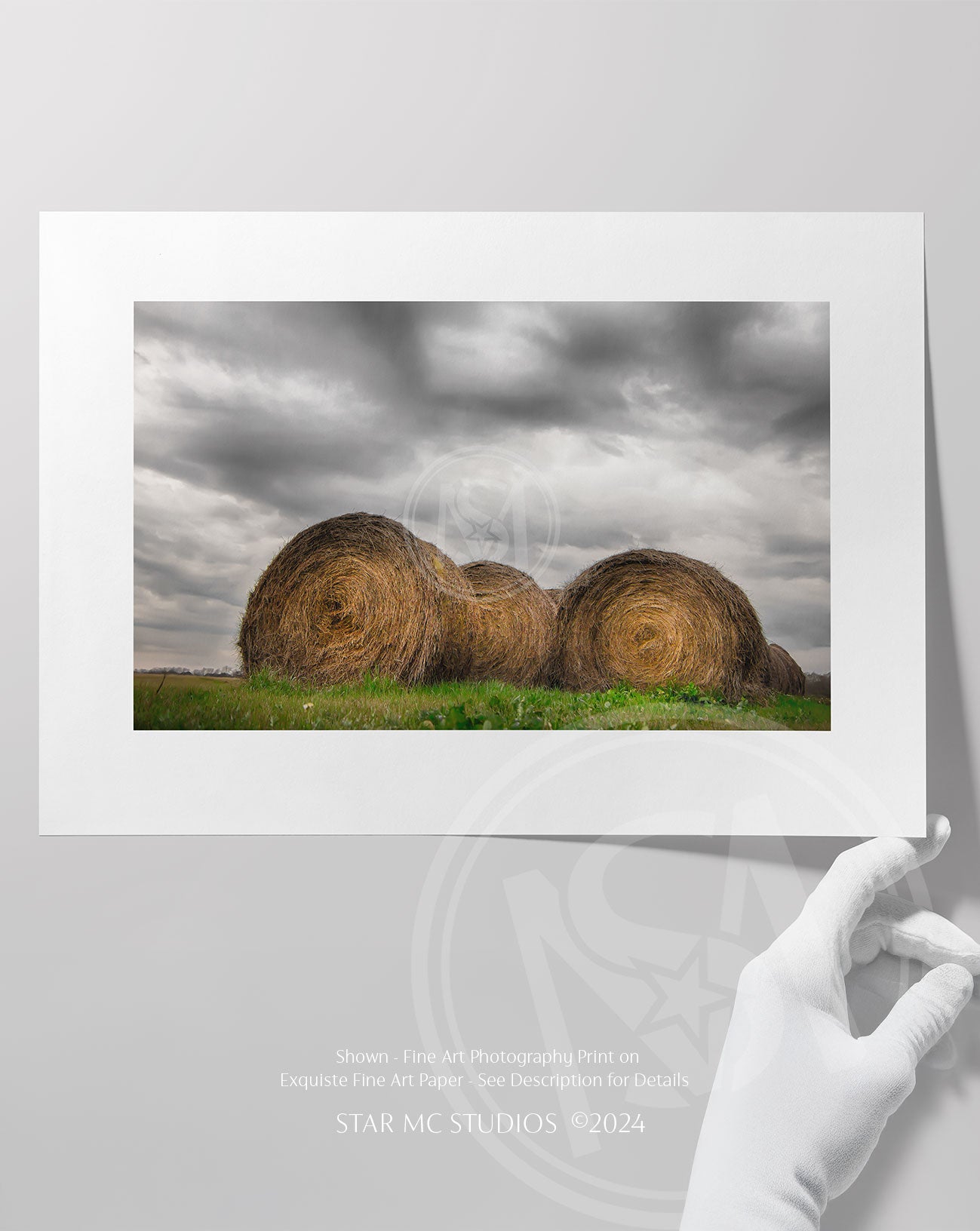 Neatly stacked hay bundles in a quiet  pasture beneath soft gray storm clouds, captured in limited edition Southern fine art photography.