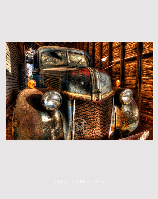 Close-up of a weathered 1941 Ford F-100 truck at dusk inside a corn shed, captured in limited edition Southern fine art photography—nostalgic and reflective.