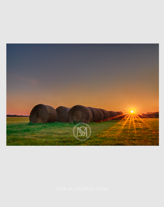 Golden hay bundles resting in a green pasture beneath a cloudy sky, captured in limited edition Southern fine art photography on museum-quality paper.